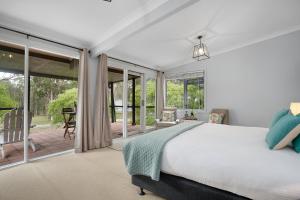 a bedroom with a bed and sliding glass doors at 27 Rows on Hermitage in Pokolbin