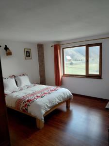 a bedroom with a bed and a large window at Cabana Țibleș Bichigiu in Bichigiu