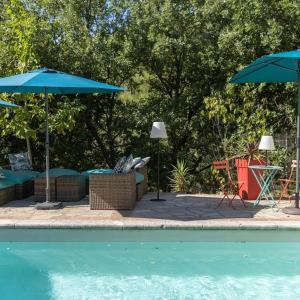 a pool with umbrellas and chairs and a table and chairs at Studio le nid avec piscine partagée in Flayosc