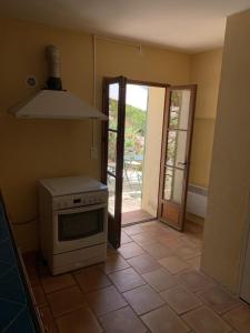 a kitchen with a stove and a door to a patio at Mas de la clue - 2 personnes in Figanières