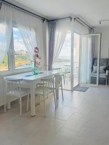 a white dining room with a table and chairs and windows at BEACH FRONT APARTMENT in CALA MARSAL with the SEA VIEW ! in Portocolom