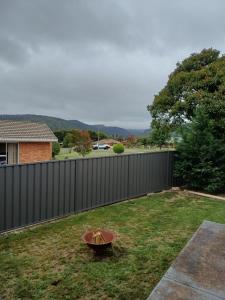 a yard with a fence and a bowl in the grass at Wattleview in Lithgow
