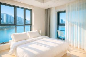 a bedroom with a white bed and large windows at 부산 엘스테이 호텔 레지던스 EL STAY Busan Long Stay Hotel Residence l 아르떼20 OFF짚라인30 OFF스릴10 OFF 할인 in Busan +106 photos