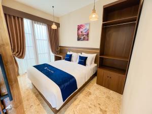 a bedroom with a large bed with blue pillows at Among Villa Demangan in Yogyakarta