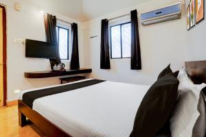 a bedroom with a bed and a tv and windows at Townhouse Amrapali Resort in Kolhapur
