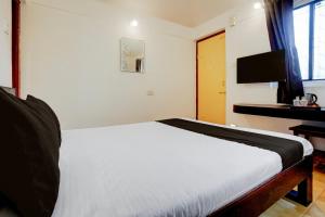 a bedroom with a bed and a desk with a television at Townhouse Amrapali Resort in Kolhapur +41 photos