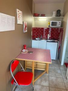 a small kitchen with a table and a red chair at Le redful in Étoile-sur-Rhône