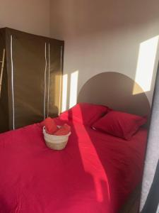 a red bed with red pillows and a basket on it at Le redful in Étoile-sur-Rhône