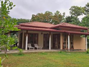 a small house with two chairs in a yard at Sansayin Homestay in Hambantota
