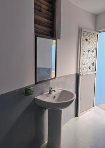 a white bathroom with a sink and a mirror at Sansayin Homestay in Hambantota
