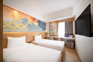 a hotel room with two beds and a flat screen tv at Metland Hotel Bekasi in Bekasi +17 photos