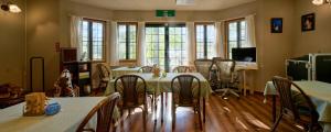 a dining room with tables and chairs and windows at カナリアンホテル in Tateshina
