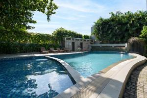 a swimming pool in a yard with chairs and trees at Metland Hotel Bekasi in Bekasi