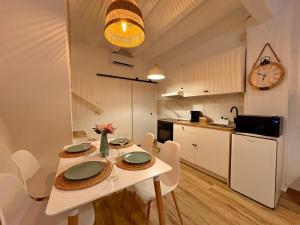 a kitchen with a white table with chairs and a clock at Las Casitas de Cullera Sol y Mar in Cullera
