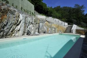 duży niebieski basen obok kamiennej ściany w obiekcie Mastena Elegante w mieście San Siro
