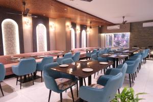 a restaurant with wooden tables and blue chairs at Hotel The Royal Keshar-Near Bhutan Border in Jaigaon
