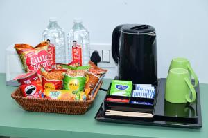 a basket of chips and snacks next to a coffee maker at Lumis Hotel Whitefield in Bangalore