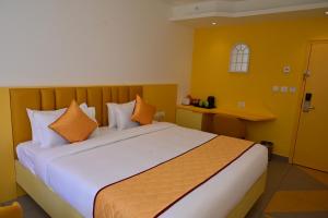 a bedroom with a bed with orange and white pillows at Lumis Hotel Whitefield in Bangalore +20 photos