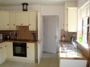 cocina con armarios blancos, fregadero y ventana en Lough Rynn Self Catering, en Mohill