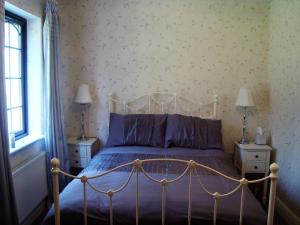 a bedroom with a bed with purple sheets and a window at Lough Rynn Self Catering in Mohill