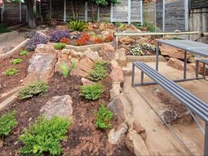 a garden with rocks and a bench and flowers at At Ease Road Lodge in Zeerust