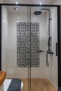 a shower with a black and white pattern on the wall at Maelia Samos Apartment in Ríva