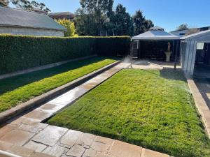 a garden with a hedge and a lawn at Alvane Cottage in Goulburn