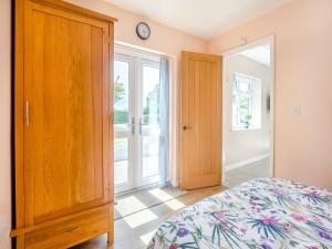 a bedroom with a bed and a wooden cabinet at Jemmett Lodge in Kent +5 photos