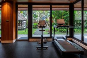 a gym with a treadmill and a elliptical machine at Puri Santrian Beach Resort And Spa in Sanur
