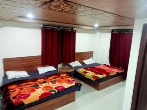 two beds in a bedroom with red curtains at Hotel Radha Krishana in Māna +5 photos