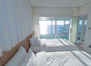 two beds in a room with a view of the ocean at 대천 아이오션 풀빌라 호텔 in Koryŏng