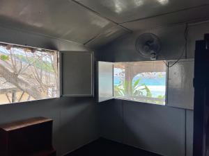 a room with a window and a table and a fan at Ohlala Guesthouse in Perhentian Islands