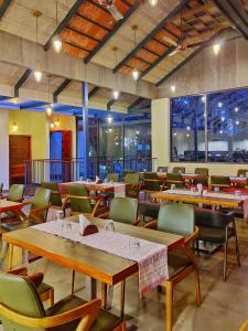 a restaurant with wooden tables and chairs and windows at Willow Resorts Wayanad in Ambalavayal
