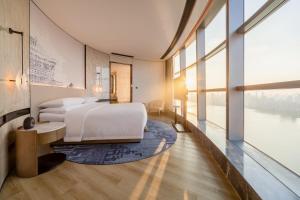 a bedroom with a bed and a large window at Wuhan Marriott Hotel Wuchang in Wuhan