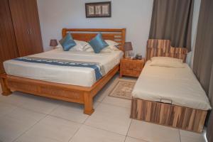 a bedroom with two beds and a chair at Surfers Cove Apartments in Bel Ombre