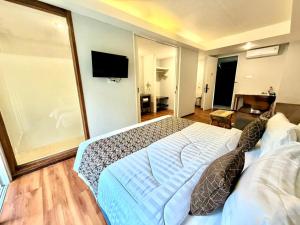 a bedroom with a large bed and a flat screen tv at Dealton Hotel Sanur in Sanur