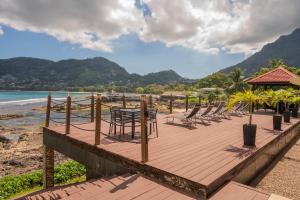 a wooden deck with chairs and tables on the beach at Surfers Cove Apartments in Bel Ombre