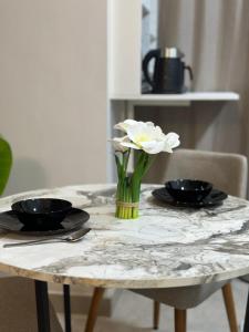 a table with two plates and a vase with flowers on it at Fully Furnished Hotel Studio for Rent in ZED Towers Sheikh Zayed in Sheikh Zayed +1 photo