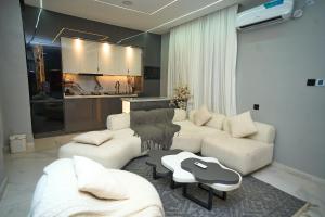 a living room with two white couches and a kitchen at Emiez Apartment and Hotel in Benin City