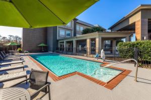 a swimming pool with chairs and an umbrella at La Quinta by Wyndham Boutte in Boutte
