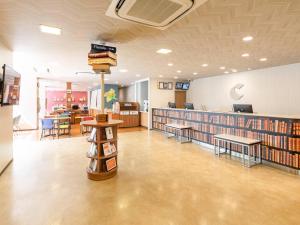 a library with bookshelves and tables and chairs at Comfort Hotel Maebashi in Maebashi