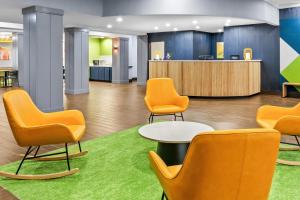 a waiting room with orange chairs and a counter at Spark by Hilton Cincinnati Fairfield in Forest Park