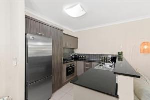 a large kitchen with a stainless steel refrigerator at Tropical Resort with balcony overlooking pool in Westcourt