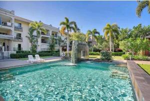 a swimming pool in front of a house at Tropical Resort with balcony overlooking pool in Westcourt