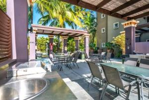 a patio with tables and chairs and palm trees at Tropical Resort with balcony overlooking pool in Westcourt