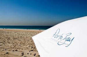 a surfboard sitting on a sandy beach with the ocean at PortoBay Rio de Janeiro in Rio de Janeiro