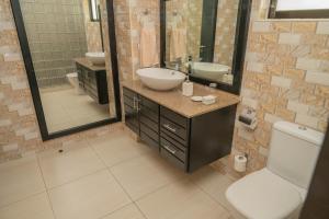 a bathroom with a sink and a toilet and a mirror at Surfers Cove Apartments in Bel Ombre +24 photos