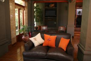 un sofá de cuero con almohadas naranjas y blancas. en Hostería Lunahuana en Tafí del Valle