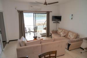 a living room with a couch and a view of the ocean at Surfers Cove Apartments in Bel Ombre