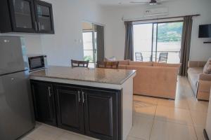 a kitchen with black cabinets and a living room at Surfers Cove Apartments in Bel Ombre